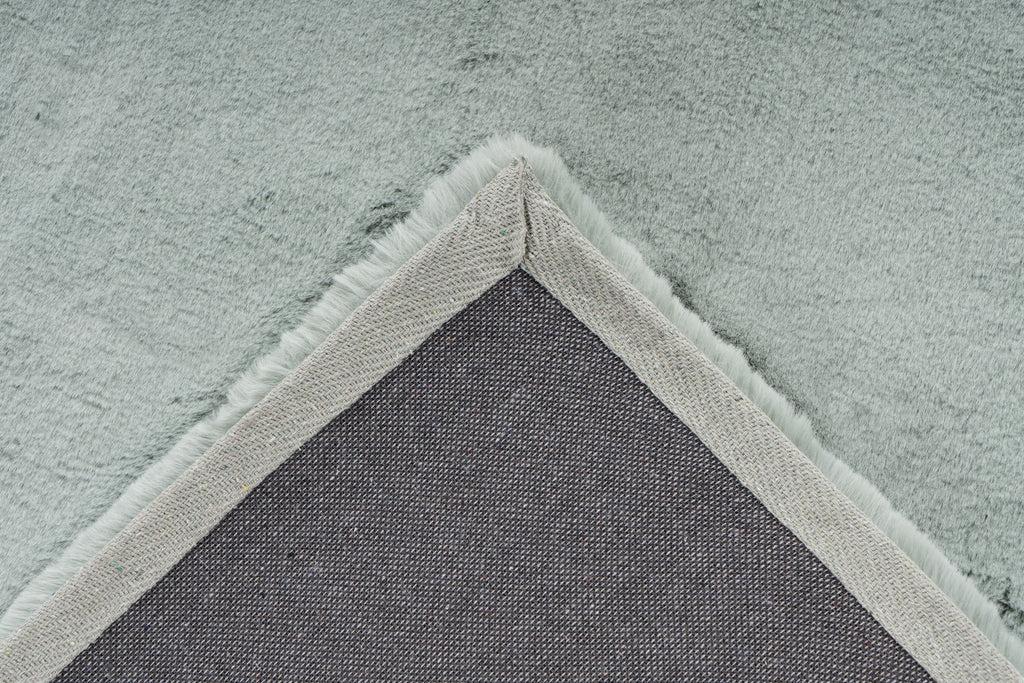 Detailopname van de backing van het mosgroene Could vloerkleed met zicht op afwerking