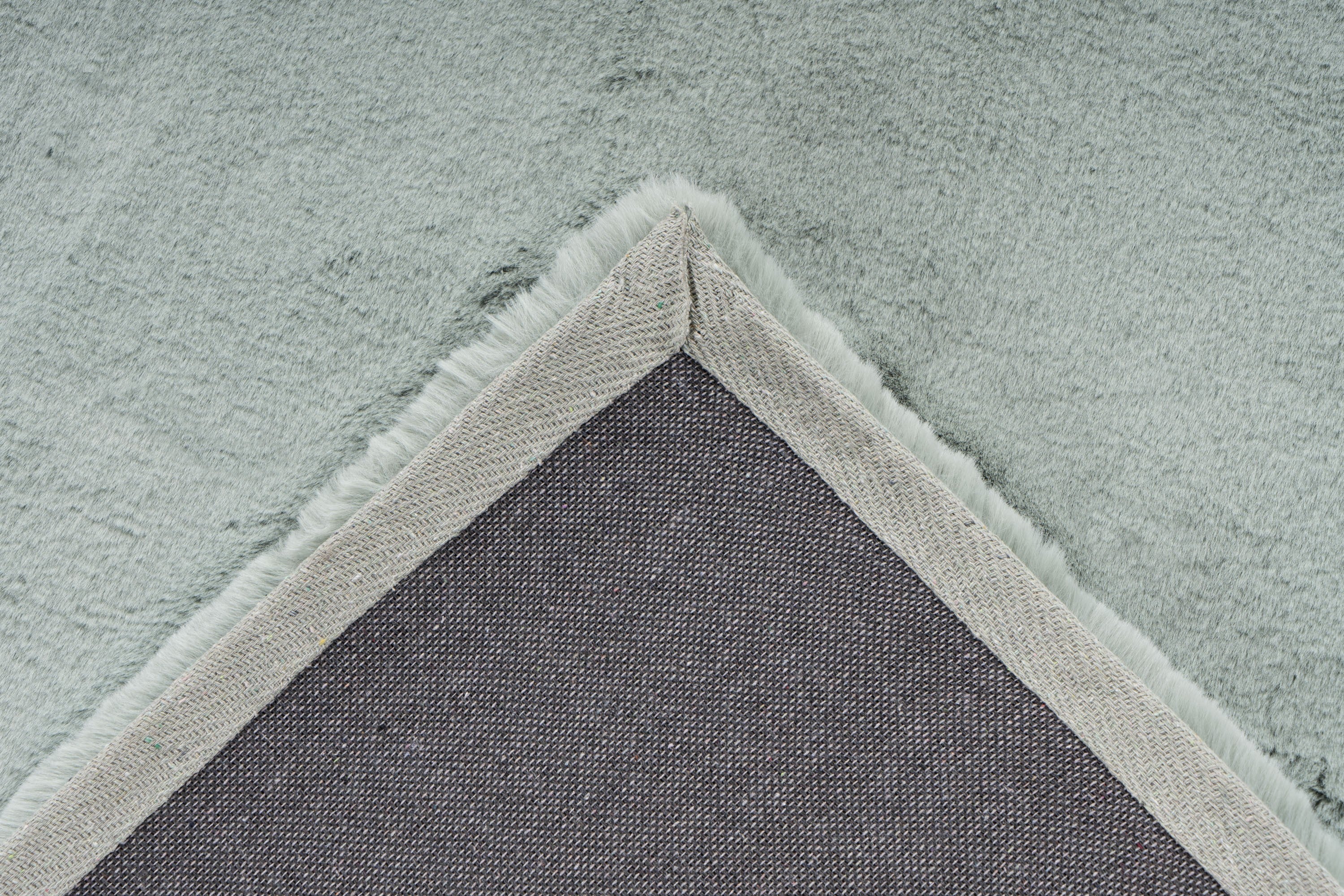 Detailopname van de backing van het mosgroene Could vloerkleed met zicht op afwerking