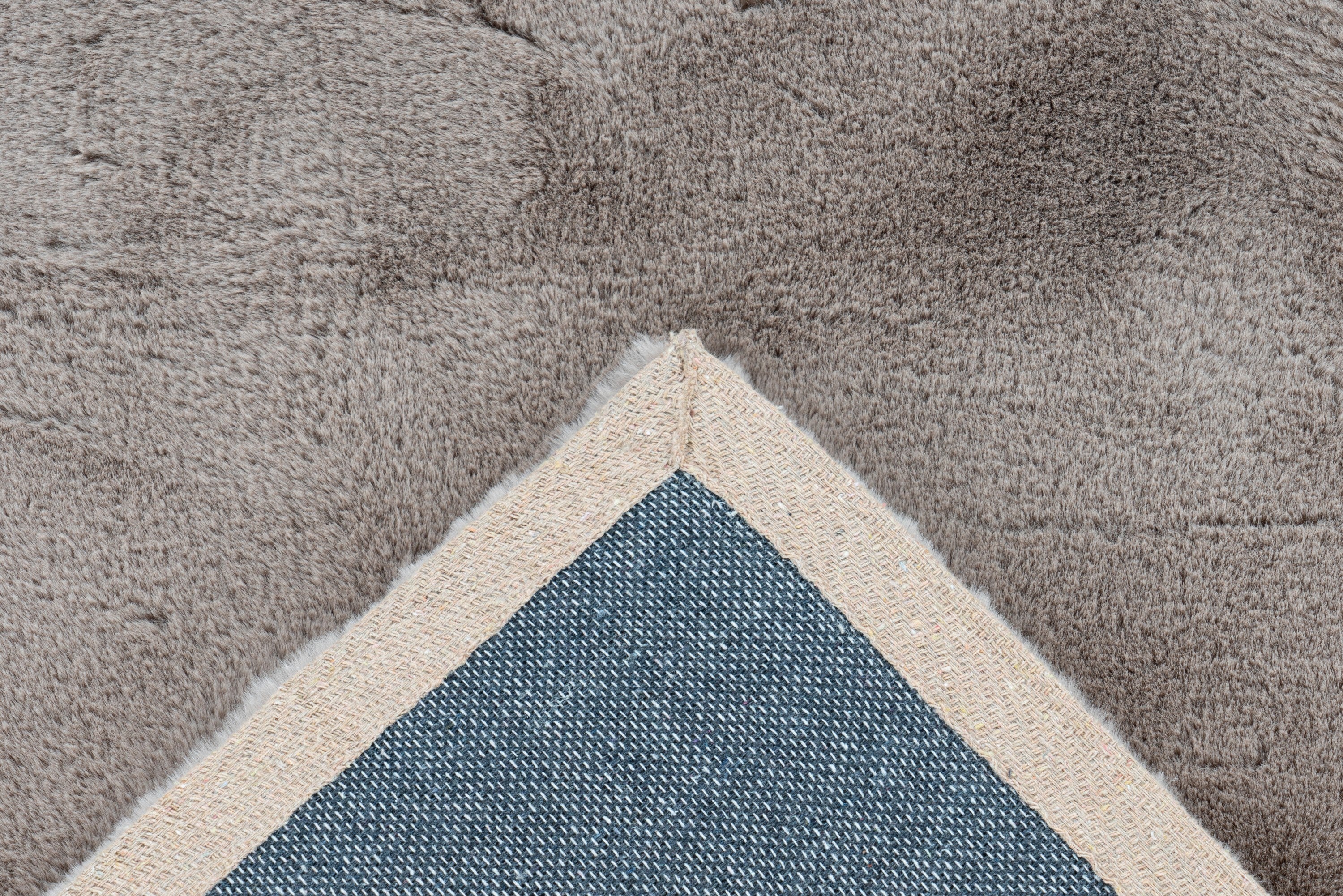 Detailopname van de backing van het Ligt taupe Could vloerkleed met zicht op de afwerking