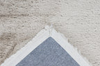 Detailshot van de onderzijde van het zandbeige Cloud vloerkleed, netjes afgewerkt