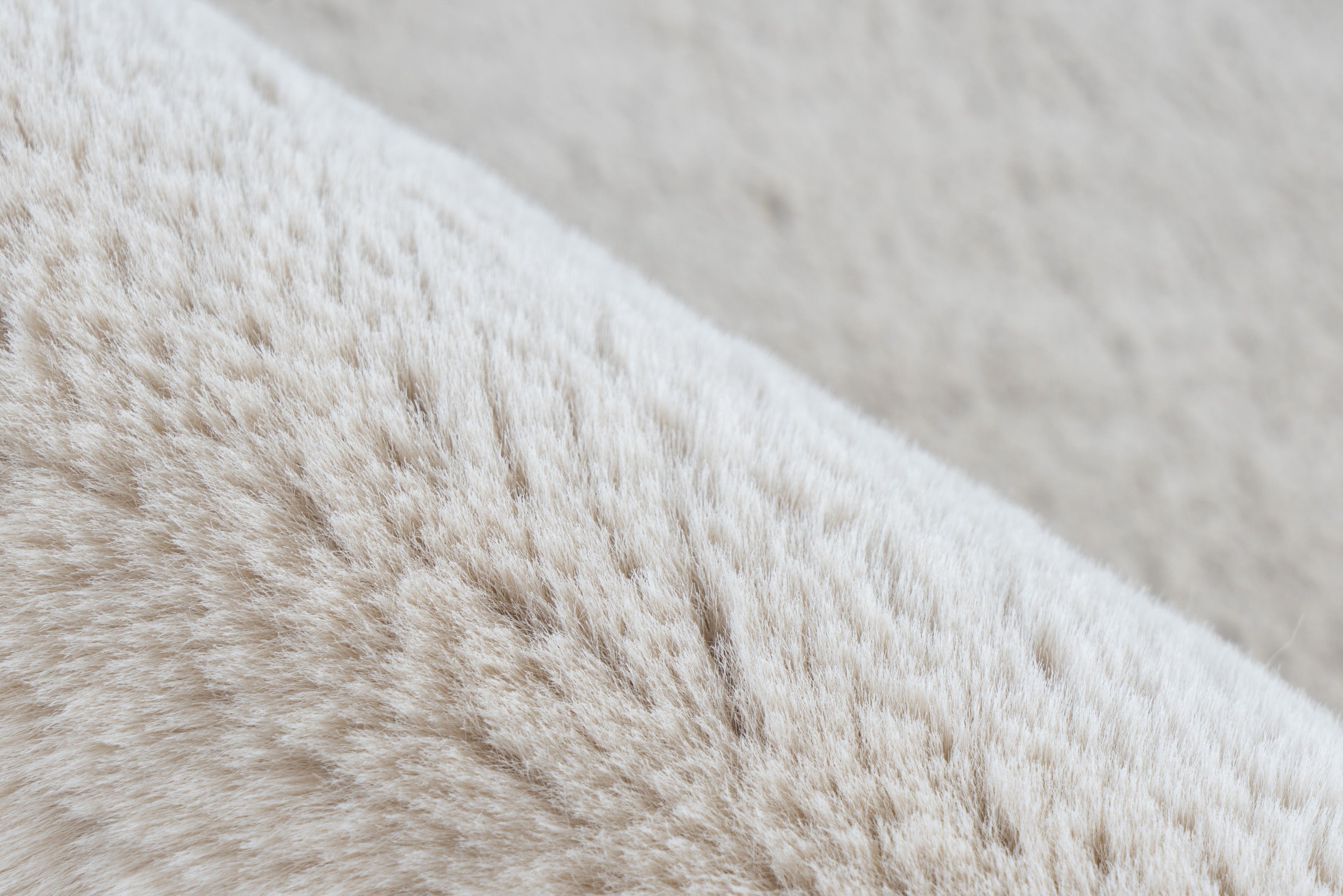 Ingezoomde opname van het oppervlak van het zandbeige Cloud vloerkleed met subtiele textuur