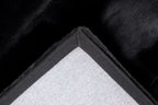 Close-up van de backing van het zwarte Could vloerkleed met zicht op de afwerking