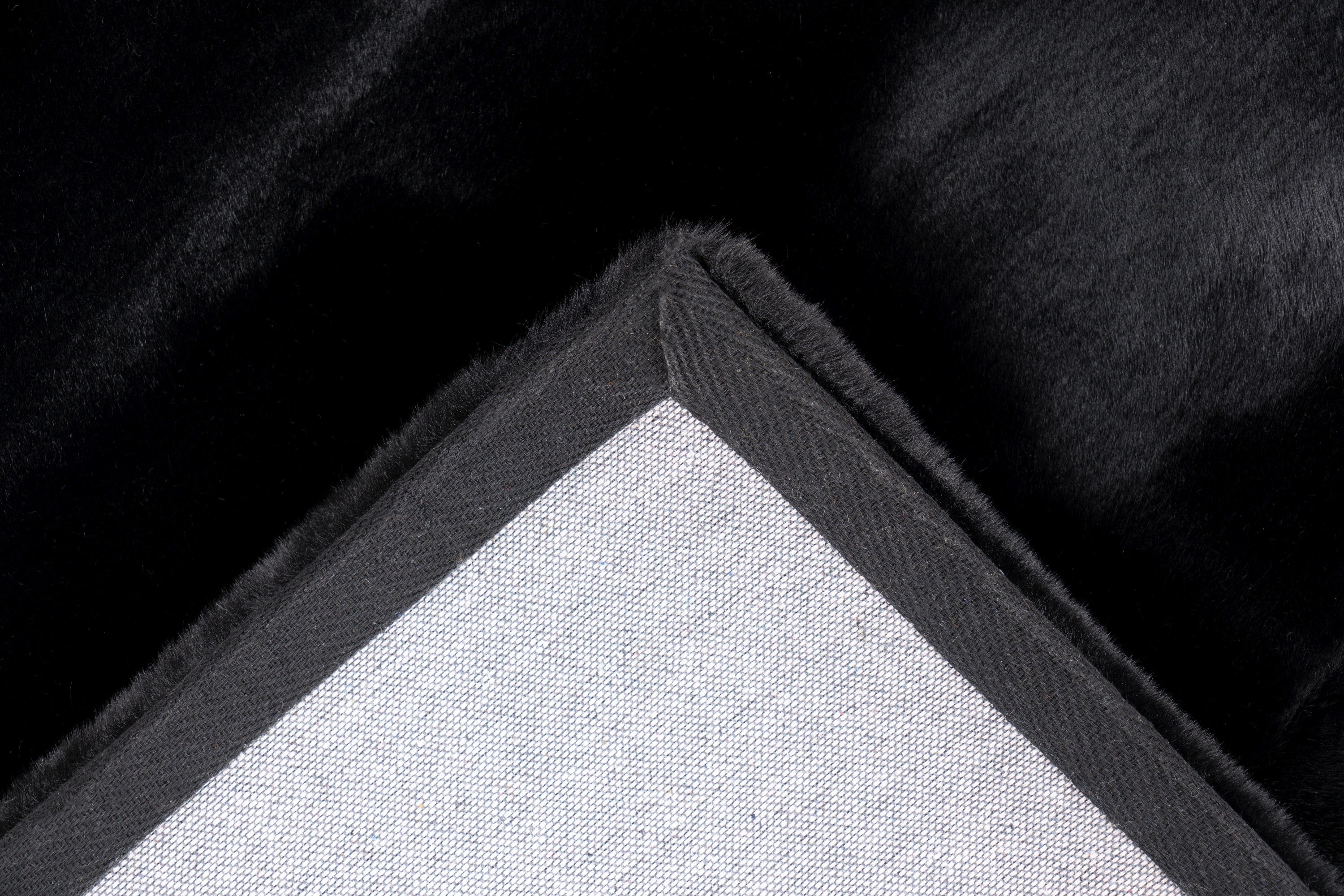Close-up van de backing van het zwarte Could vloerkleed met zicht op de afwerking
