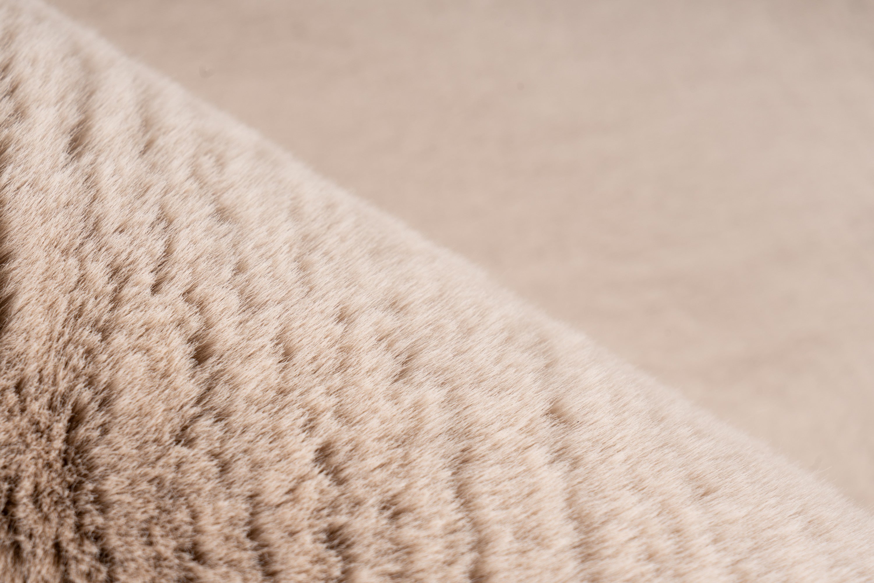 Close-up van de fijne vezels van het beige Eternelle vloerkleed, met warme uitstraling