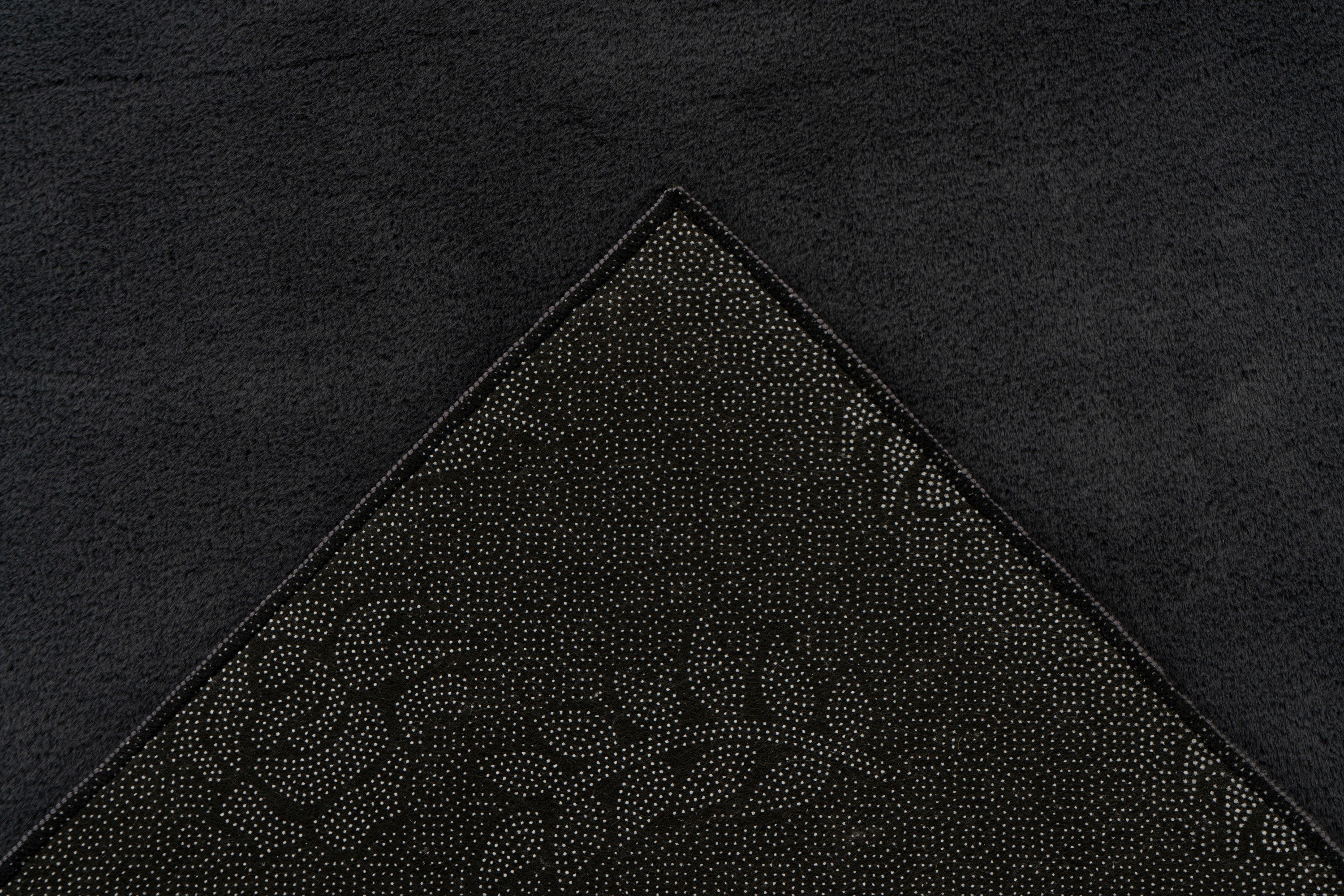 Detailhoek van vloerkleed met zicht op de backing – Softcare product op de achtergrond