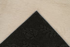 Ingezoomde hoek van beige Softcare vloerkleed met zicht op de backing