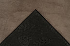 Ingezoomde hoekopname van taupe vloerkleed met zicht op de backing
