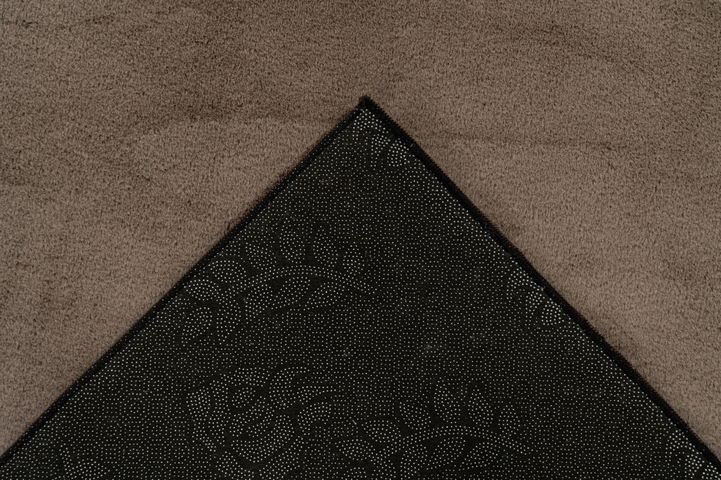 Ingezoomde hoekopname van taupe vloerkleed met zicht op de backing