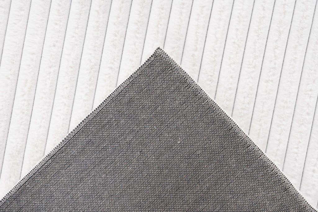Close-up van een hoek van het witte Lushlyn vloerkleed met zicht op de backing