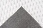 Close-up van een hoek van het witte Lushlyn vloerkleed met zicht op de backing