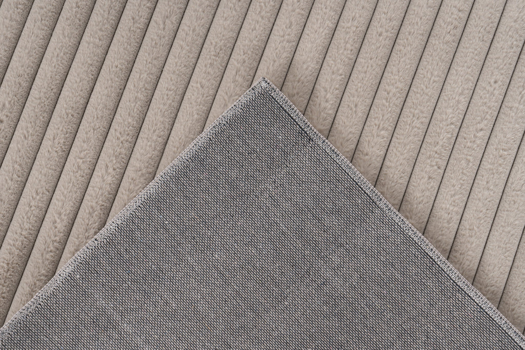 Ingezoomde hoek van taupe Lushlyn vloerkleed met zicht op backing en afwerking