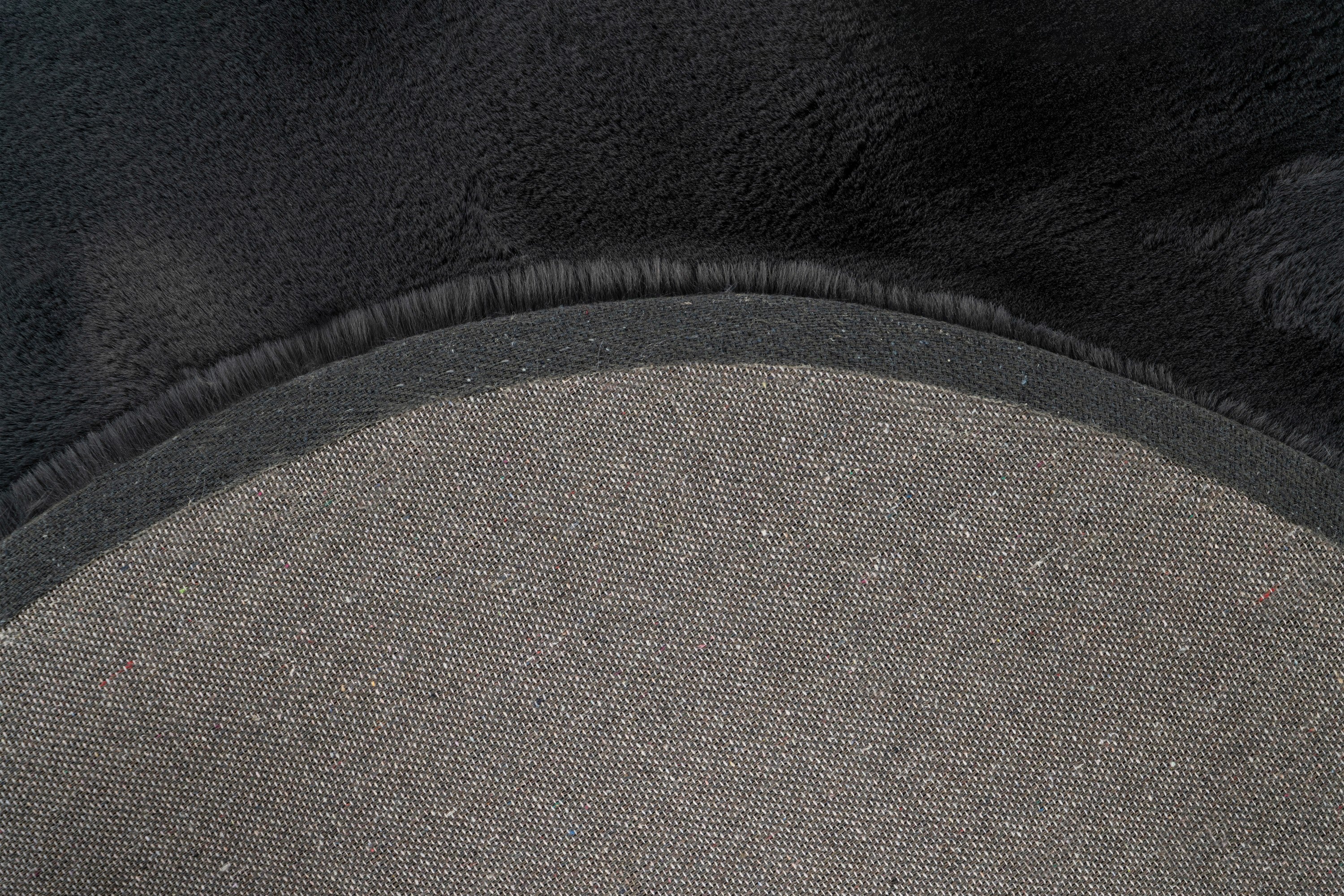 Close-up van de backing van het antraciet Maan vloerkleed met zicht op de afwerking