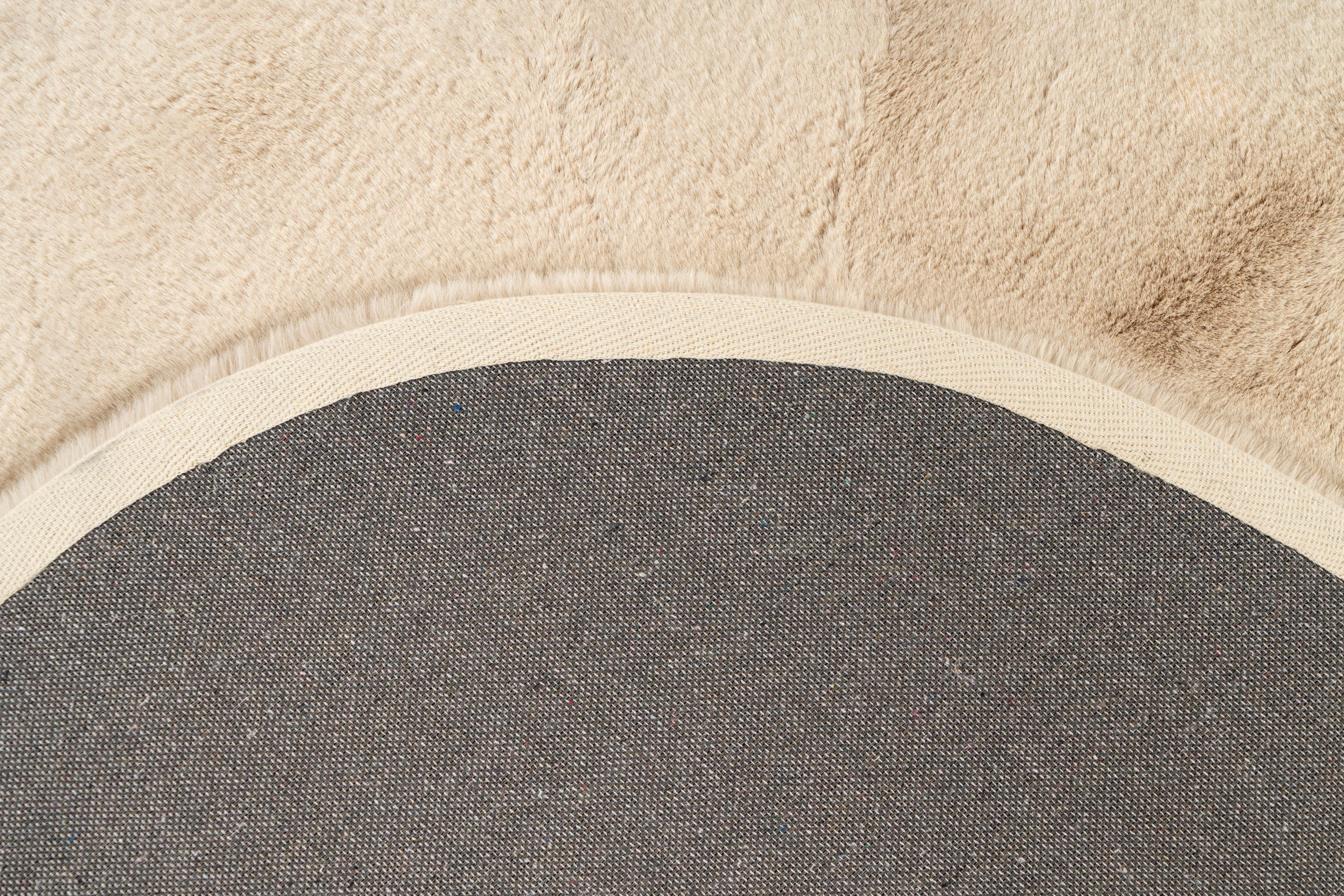 Detailopname van de achterkant van het zandbeige Maan vloerkleed met zicht op de afwerking
