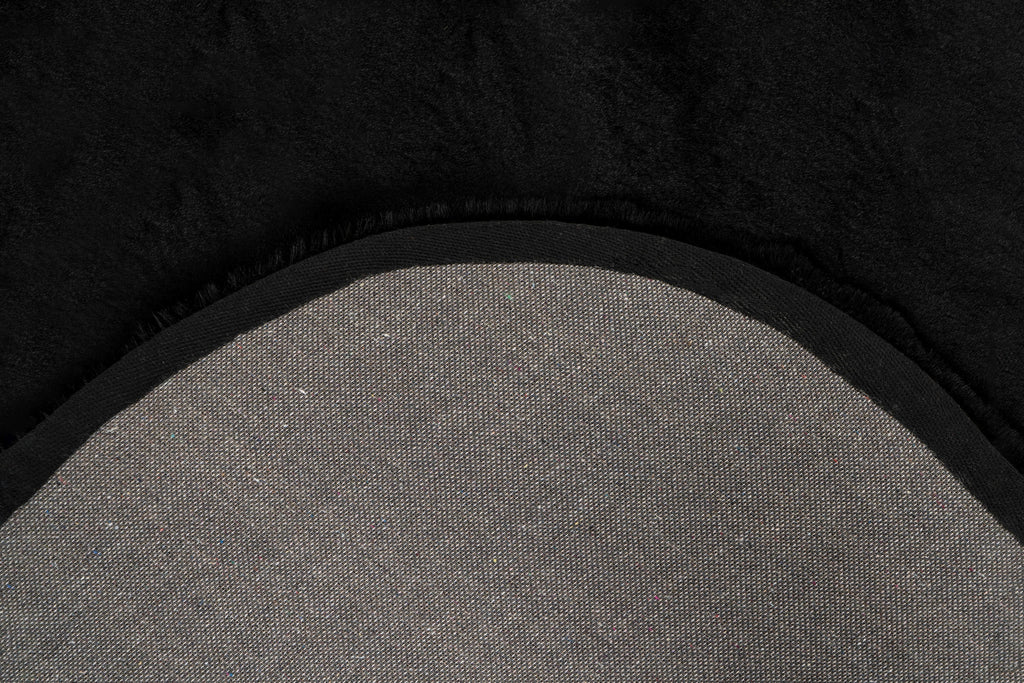 Close-up van een hoek van het Maan zwart vloerkleed met zicht op de afgeronde vormen en backing