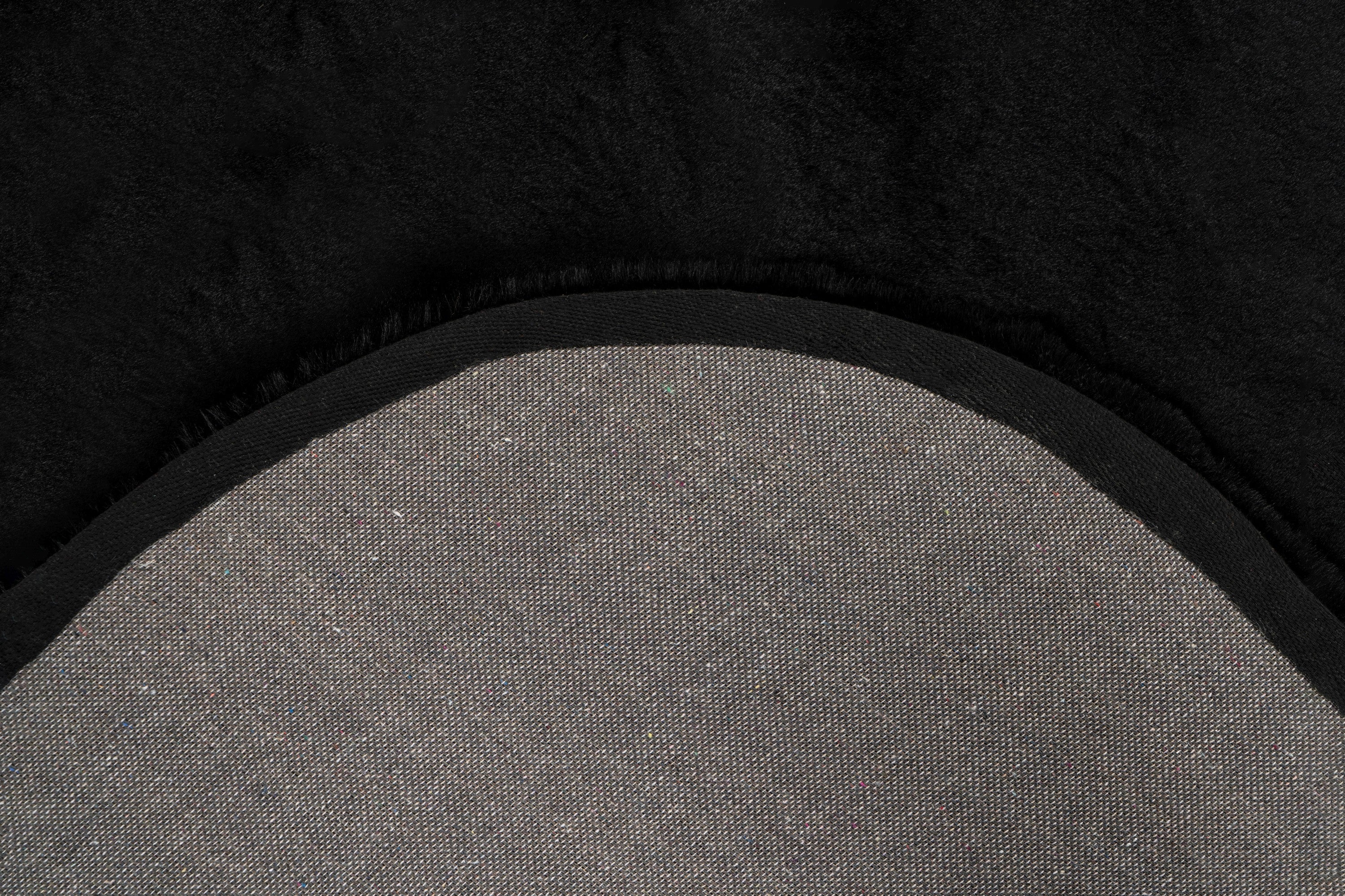 Close-up van een hoek van het Maan zwart vloerkleed met zicht op de afgeronde vormen en backing