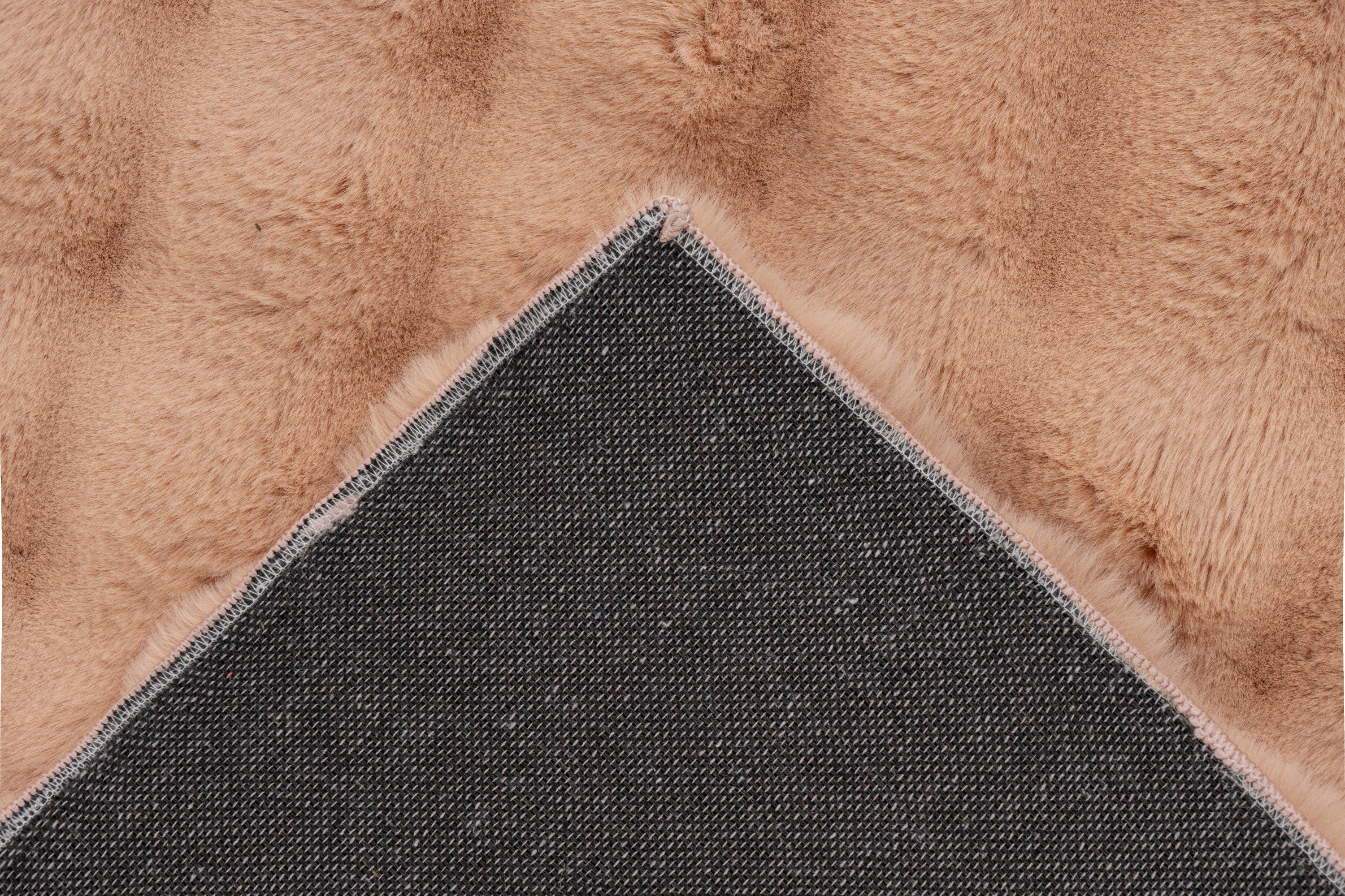 Close-up van een hoek van het perzik Softedge vloerkleed met zicht op de backing