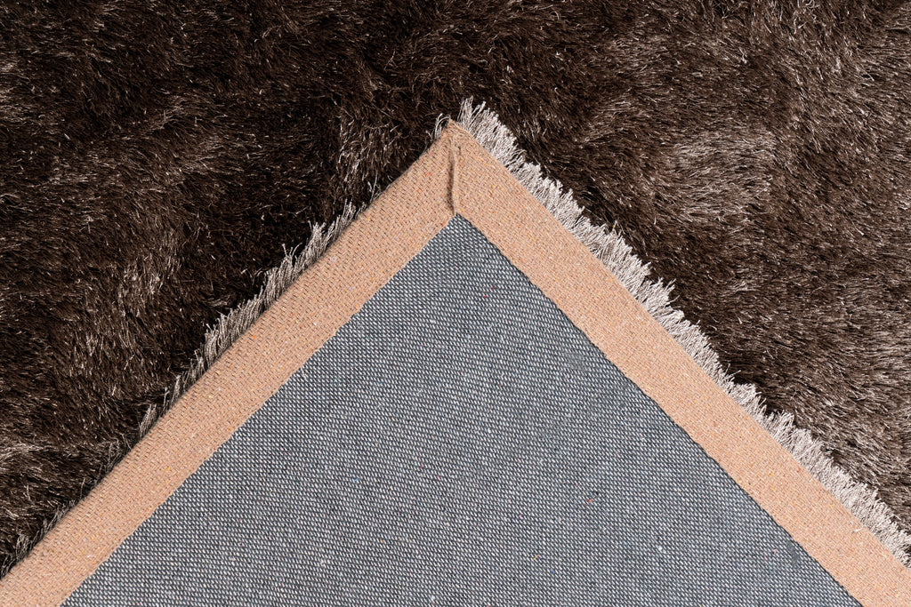 Ingezoomde hoek van bruin Softwave vloerkleed met zicht op backing en afwerking