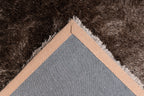 Ingezoomde hoek van bruin Softwave vloerkleed met zicht op backing en afwerking
