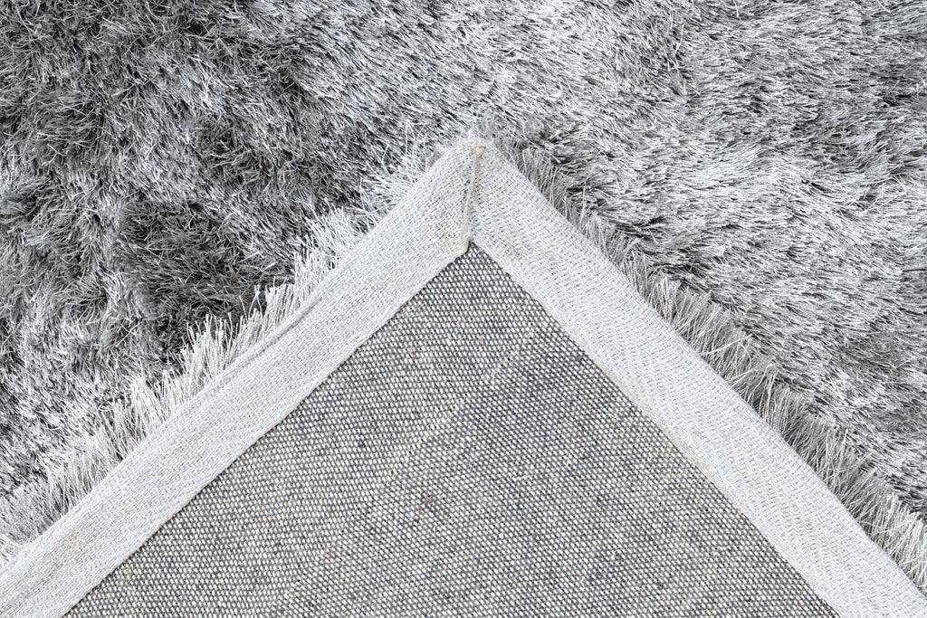 Ingezoomde hoek van zilvergrijs Softwave vloerkleed met zicht op backing