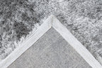 Ingezoomde hoek van zilvergrijs Softwave vloerkleed met zicht op backing