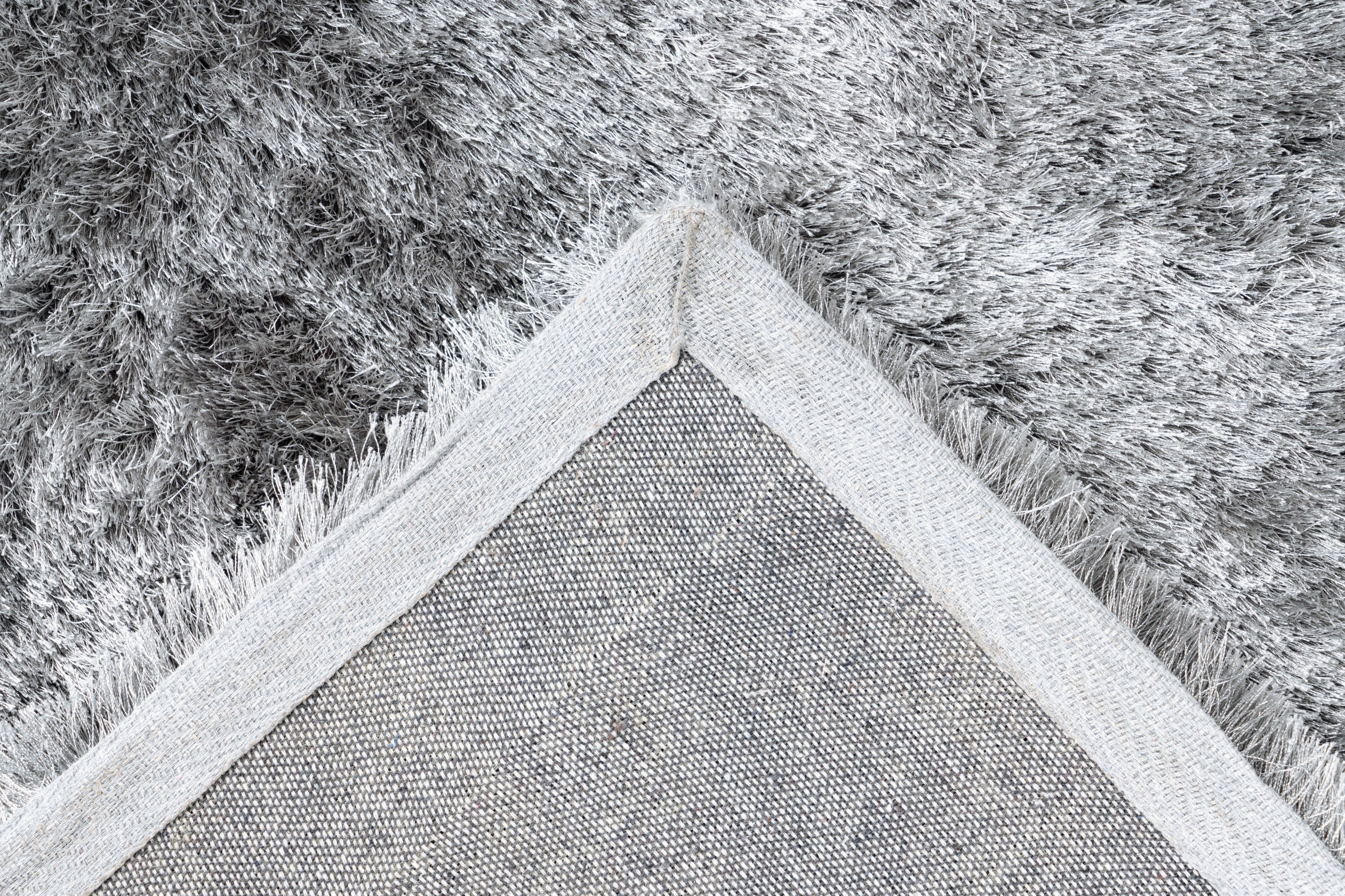 Ingezoomde hoek van zilvergrijs Softwave vloerkleed met zicht op backing