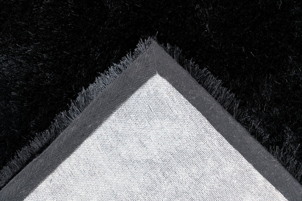 Ingezoomde hoek van zwart Softwave vloerkleed met zicht op backing en afwerking