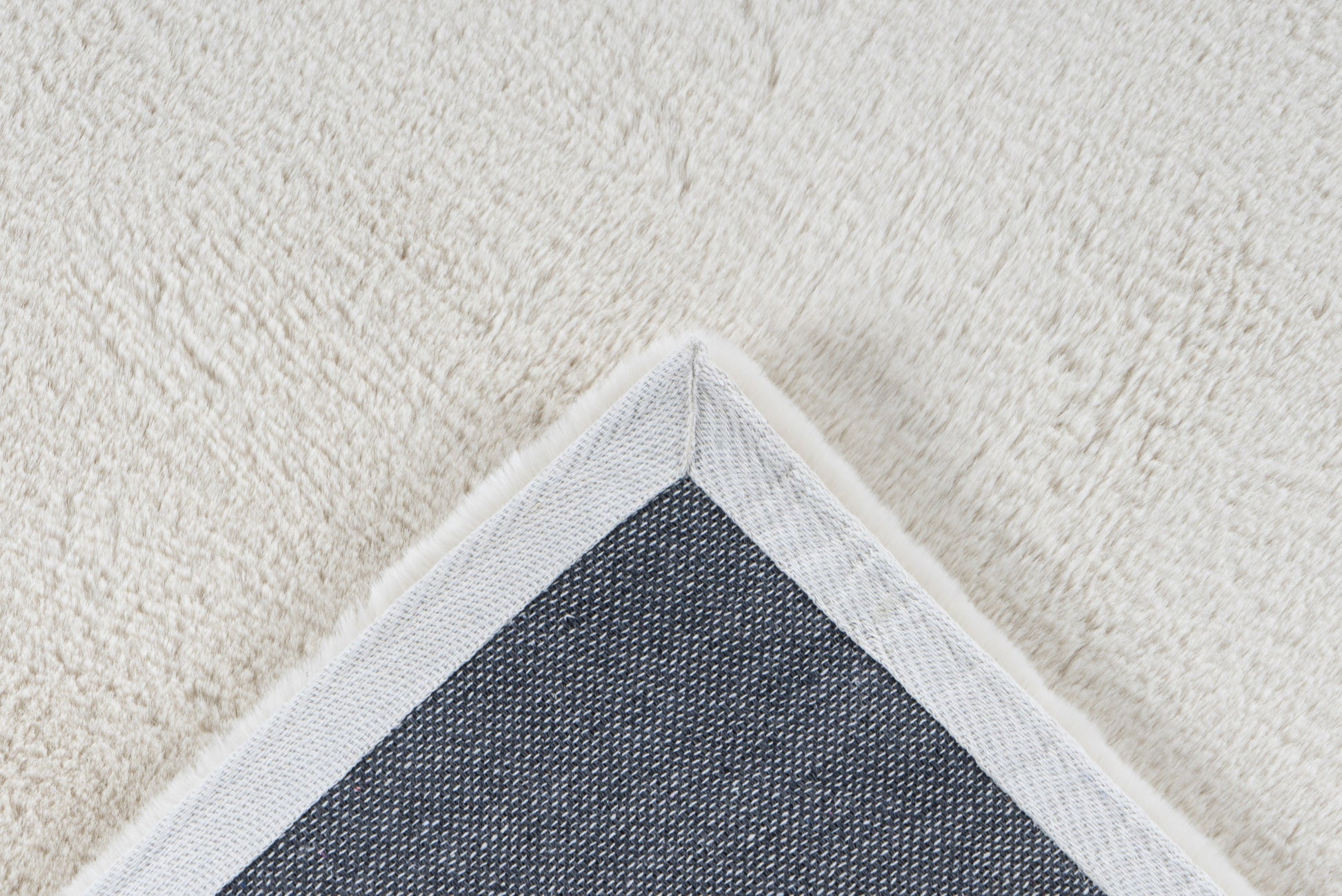 Close-up van een hoek van het crème Vellyn vloerkleed met zicht op de backing