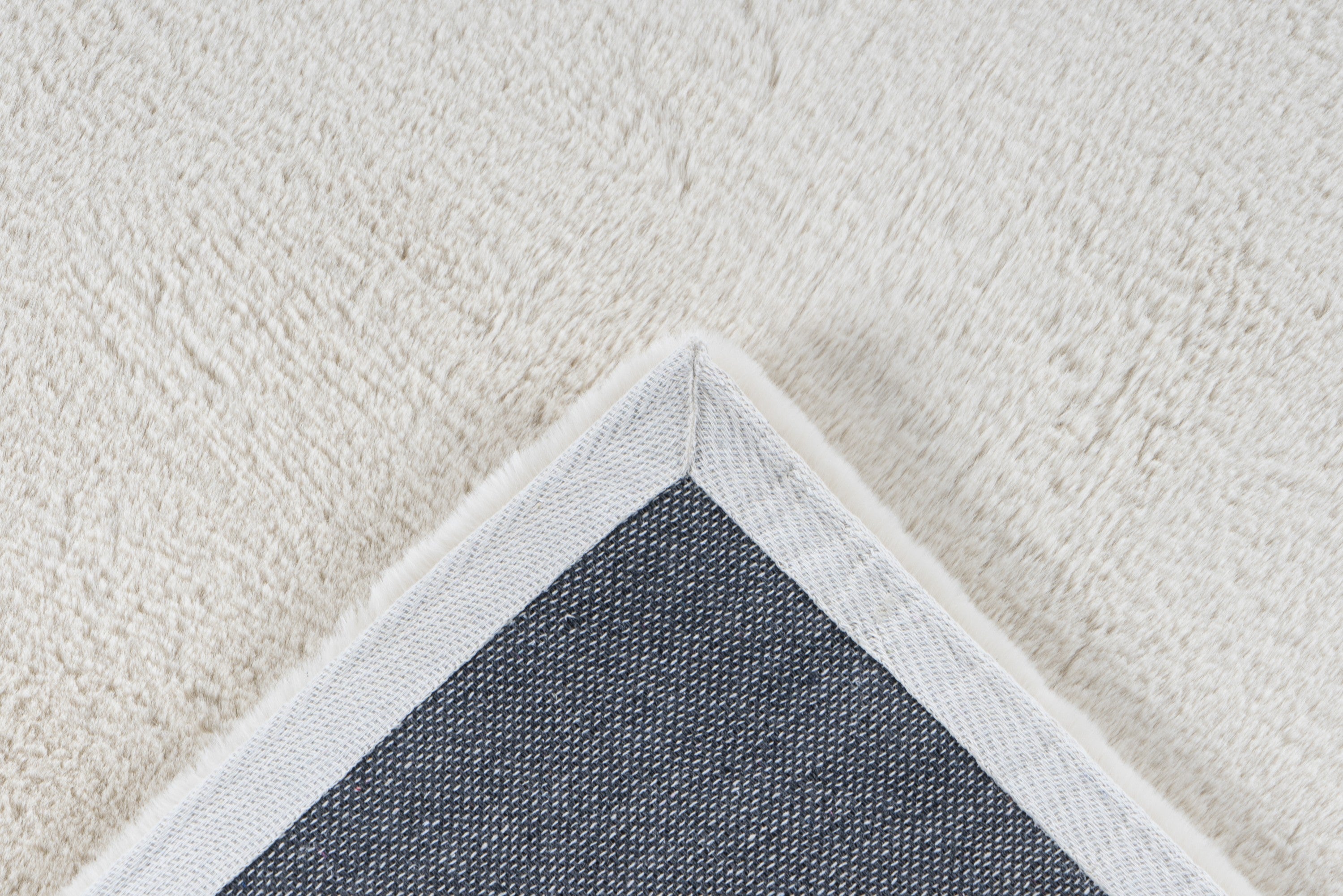 Close-up van een hoek van het crème Vellyn vloerkleed met zicht op de backing
