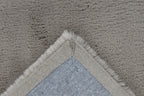Close-up van een hoek van het taupe Vellyn vloerkleed met zicht op de backing